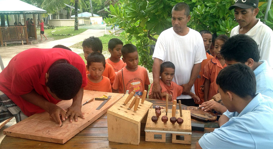 Trainees show off their newly-learned carving skills to a group of visiting school children.